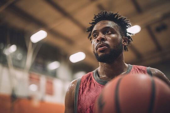 Worried African American basketball player holding ball indoors, anticipation, nervousness and stress before game concept
