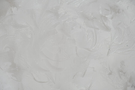 Applying decorative putty. White abstract texture of surface covered with putty. textured background of filler paste applied with putty knife in irregular dashes and strokes. Rough surface plaster