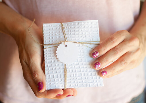 Close-up of a woman with a polka dot manicure holding a wrapped gift