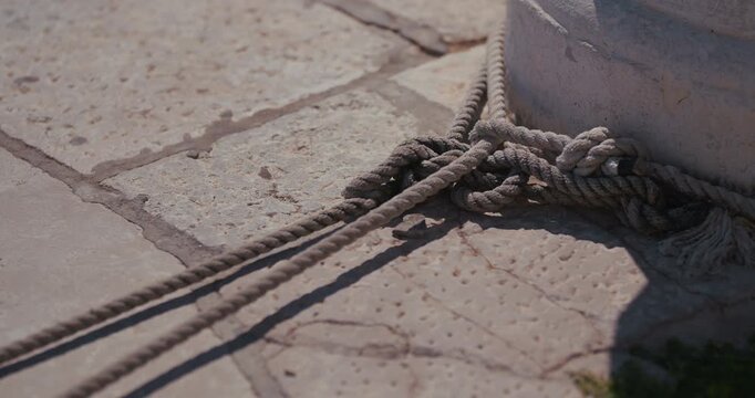 Close up of mooring rope tied on a stone waterfront surface in Rovinj, Croatia.