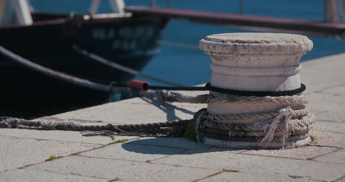 Close up of a mooring bollard with ropes on a waterfront dock in Rovinj, Croatia.