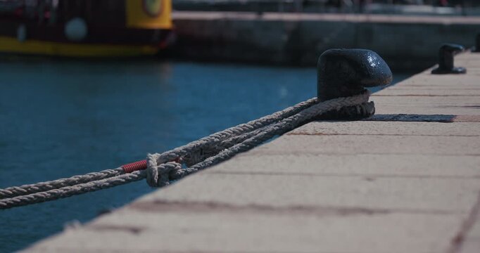 Close up of mooring ropes tied to a dock cleat on a waterfront dock in Rovinj, Croatia.