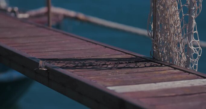 Close up of the shadow of a rope net on a wooden gangway above the water in Rovinj, Croatia.