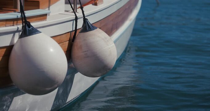 Close up of boat fenders hanging beside a wooden boat on the water in Rovinj, Croatia.