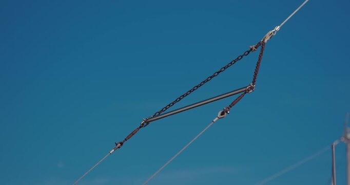 Close up of boat rigging cables and metal tension hardware against a clear blue sky in Rovinj, Croatia.