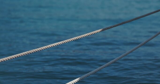 Close up of mooring ropes stretched above blue harbor water in Rovinj, Croatia.