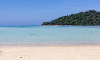 Fototapeta premium Mai Ngam Beach, Koh Surin, Thailand. Tropical paradise with clear turquoise water. Sandy shoreline, lush greenery, and tranquil ocean view.