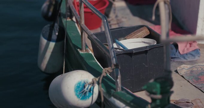 Close up of fishing equipment, plastic containers and fenders on a moored boat deck in Rovinj, Croatia.