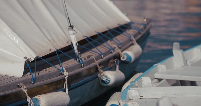 Close up of a covered wooden boat with fenders moored beside another boat in a marina in Rovinj, Croatia.