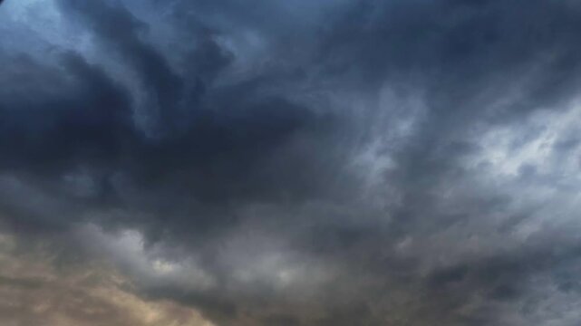 Dark storm clouds swirl across sky. Thunderheads gather before rain. Moody blue tones dominate scene. Nature's raw power captured in motion. Clouds move slowly over horizon
