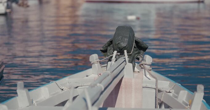 Close up front view of a covered outboard motor on a wooden boat moored on calm water in Rovinj, Croatia.