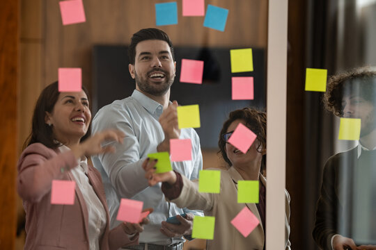 Business team planning project using sticky notes on glass wall
