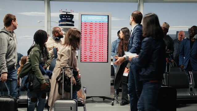 Multiethnic crowd in airport waiting for departure gate to open after global disruption delays flights. Tourists upset by cancelled international flight in air transportation transit hub, camera A