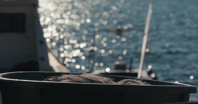 Fishing net inside a container with blurred sea and boat in the background at harbor in Rovinj, Istria, Croatia.