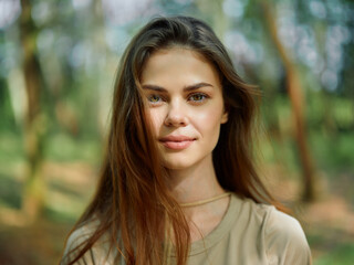 Fototapeta premium woman portrait outdoors nature forest smile young brunette with loose hair and soft natural sunlight, closeup headshot capturing warm expression, relaxed pose and shallow bokeh background for