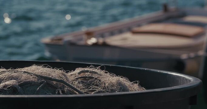 Fishing net piled inside a container with blurred boat and sea in the background at harbor in Rovinj, Istria, Croatia.