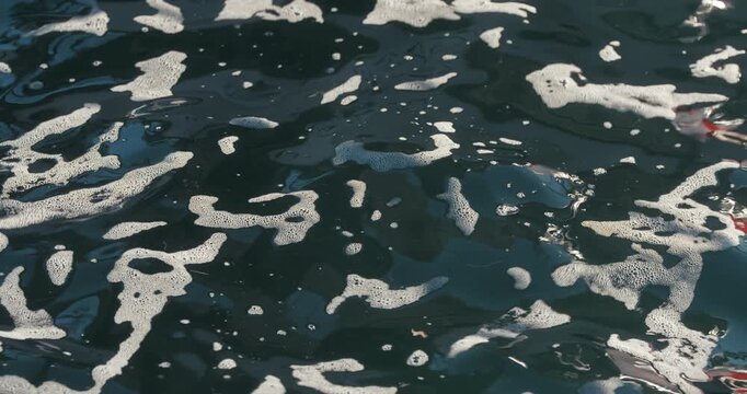 Close-up of sea foam floating on dark water surface at harbor in Rovinj, Istria, Croatia.
