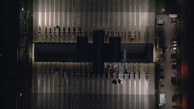 Drone shot of a motorway toll gate at night, illuminated infrastructure, top view.