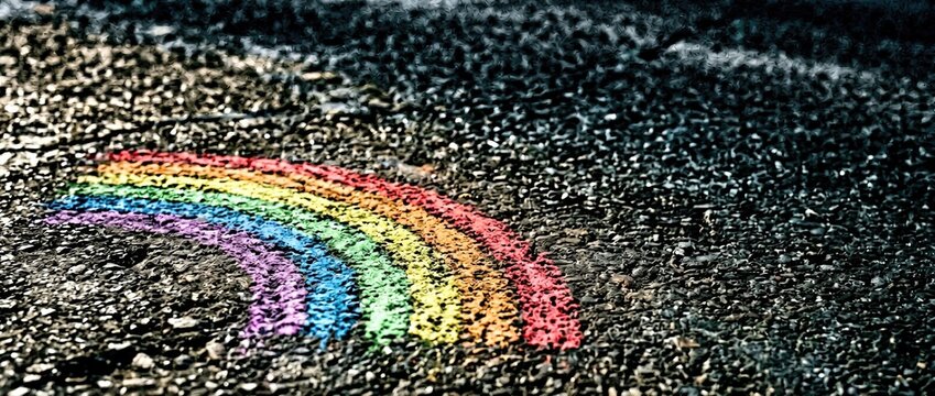 Chalk rainbow art installation on asphalt street urban environment colorful creativity captured from a ground-level perspective