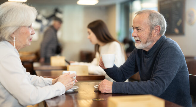 Mature couple communicate and chatting during date in cafe, have rendezvous, lovers tryst. Participants of meeting get to know each other, joke and communicate during meeting