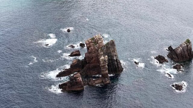 Aerial view of jagged rock formations and sea stacks at Silence Beach with waves crashing against the dark cliffs Asturias, Asturias, Spain.