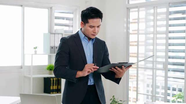 Confident young businessman auditing revenue report and planning budget while working at desk in office.