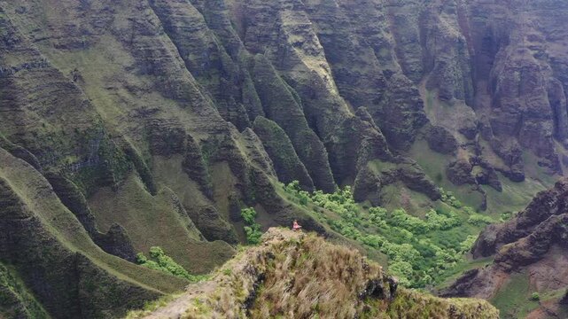 Epic woman on cliff edge Na Pali Coast, aerial, Kauai, Hawaii