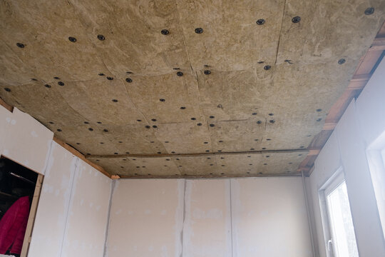 Insulated ceiling panels are visible in a room with unfinished drywall and a window, highlighting the construction materials and techniques used