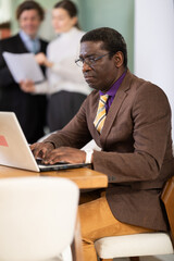 Obraz premium Confident man working online while checking reports of subordinates during a meeting in the company office