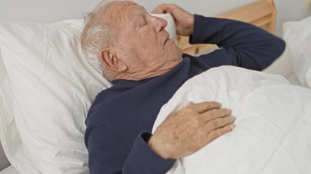 Man lying in bed with hand on pillow and mouth open, raising arm while reclining against wooden headboard in building;vulnerability.