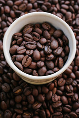 Fototapeta premium Vertical Close Up of Premium Roasted Coffee Beans in White Ceramic Espresso Cup