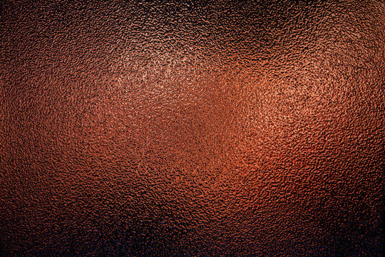 Copper colored frosted glass texture with a rough bumpy surface and warm gradient light