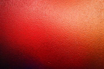 Fototapeta premium Vibrant red and orange illuminated frosted glass texture background with dark gradient