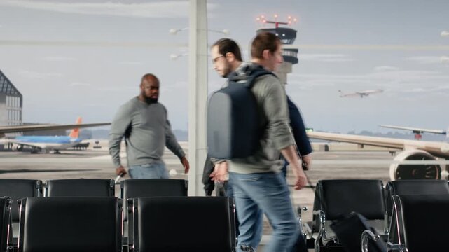 Travelers walking in busy airport departure terminal, carrying trolleys. People preparing to fly home during holiday rush, navigating through metal benches rows with luggage