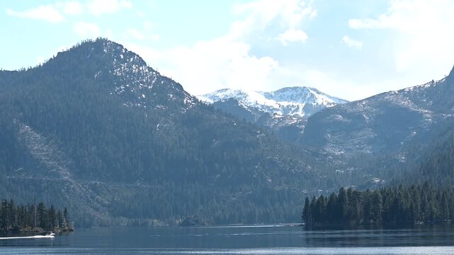 4K HD video zooming in on the mouth of Emerald Bay in Lake Tahoe, speed boat entering the bay, snow capped mountains in the background on a sunny spring day. View from the water.
