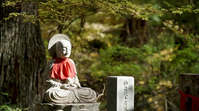 Stone Jizo Bosatsu Statue Wearing Red Bib in a Japanese Temple Garden