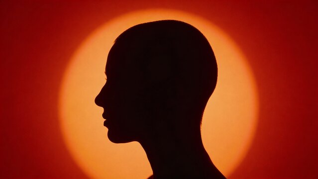 Silhouette profile with orange halo on red background for editorial, fashion and conceptual use