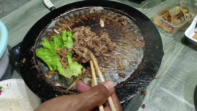 Sizzling Meat on Korean BBQ Grill with Fresh Lettuce