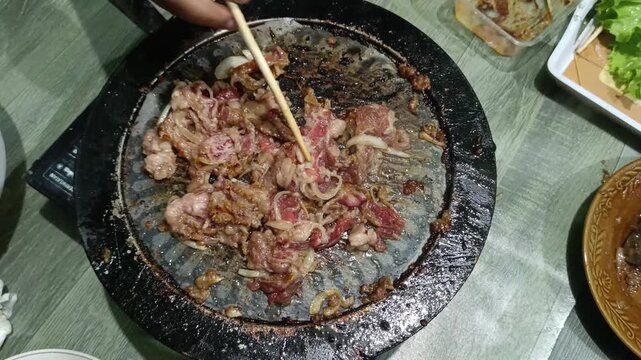 Cooking Sliced Beef with Onions on a Hot Tabletop Grill