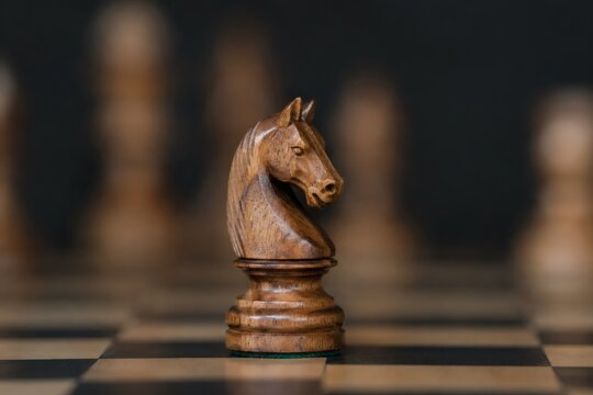 Wooden knight chess piece in sharp focus representing business strategy and leadership