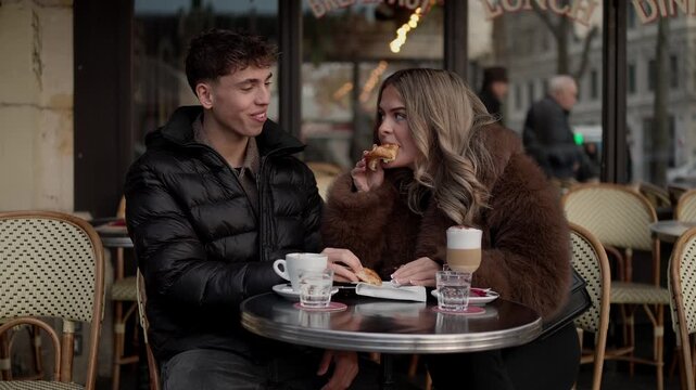 A romantic couple enjoys breakfast at an outdoor in Paris France The woman is eating a croissant while the man drinks coffee The scene captures a moment of love and connection in the heart of Paris.