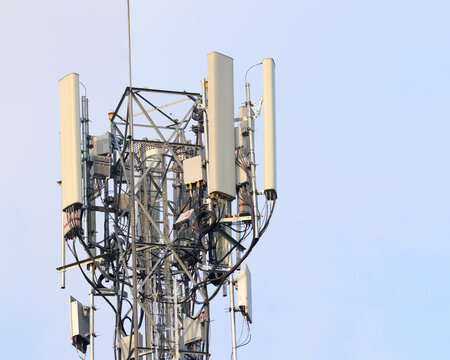 Close up modern telecom base station featuring sector antenna panels, RF cables, radio units and steel framework for mobile network transmission technology infrastructure