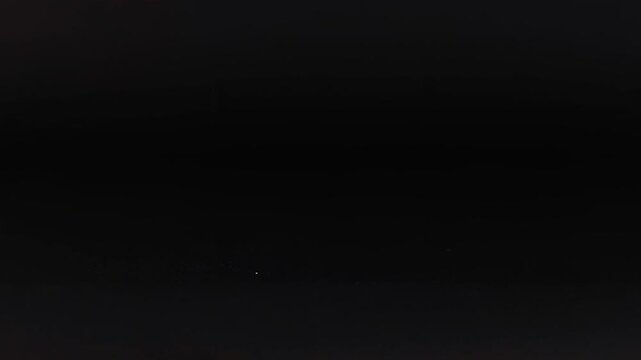 Small soccer ball rolling across dark surface in slow motion on black background.