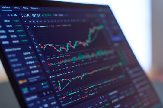 Stock market chart displayed on laptop screen on dark desk
