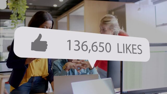 3 coworkers crowding laptop watching likes bubble appearing numbers climbing tracking campaign