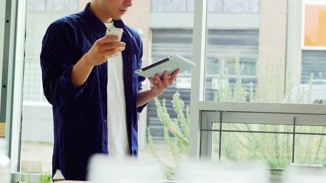 Creator by window holding tablet, phone, tapping phone while subscribe bar moving, boosting subs