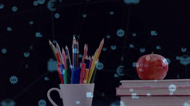 Camera moving downward, revealing pencil cup, apple on books, blue icons drifting, showing commerce