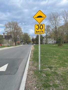Yellow speed bump sign with thirty kilometers speed limit.