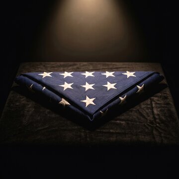 Solemnly Folded American Flag with White Stars on a Dark Velvety Surface Under Soft Spotlight