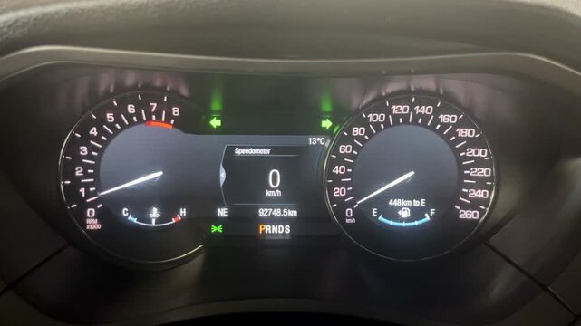 Illuminated car dashboard with active hazard warning light indicators.